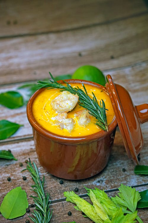 A bowl of soup with herbs and a spoon