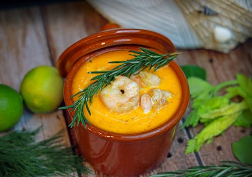 A bowl of soup with shrimp and herbs