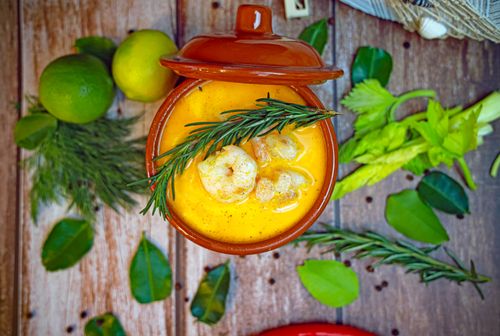 Free A top-down view of a creamy shrimp bisque garnished with rosemary, surrounded by fresh herbs. Stock Photo