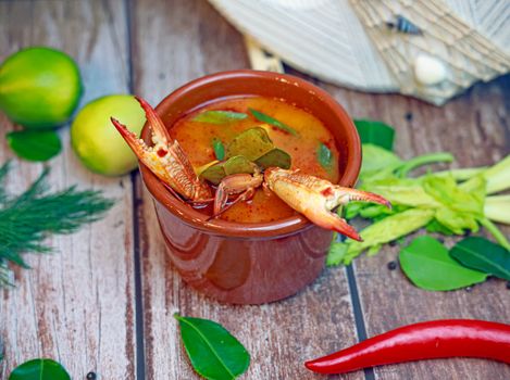A savory bowl of spicy crab soup garnished with fresh herbs and spices on a rustic table.