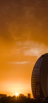 Contemporary urban architecture silhouetted by a vivid orange sunset.