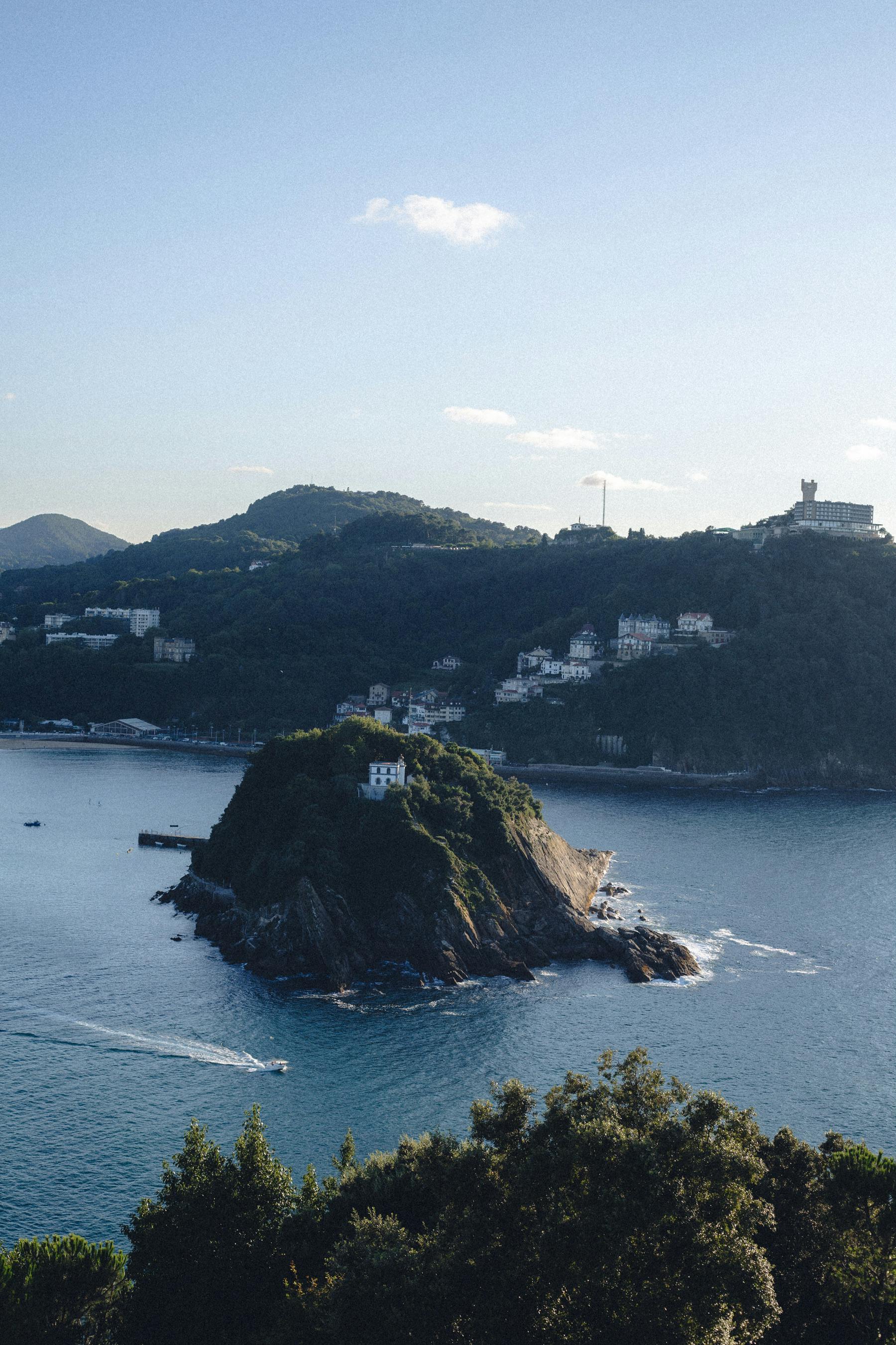 Scenic aerial view of Santa Clara Island with lush greenery and clear blue waters in San Sebastian, Spain.