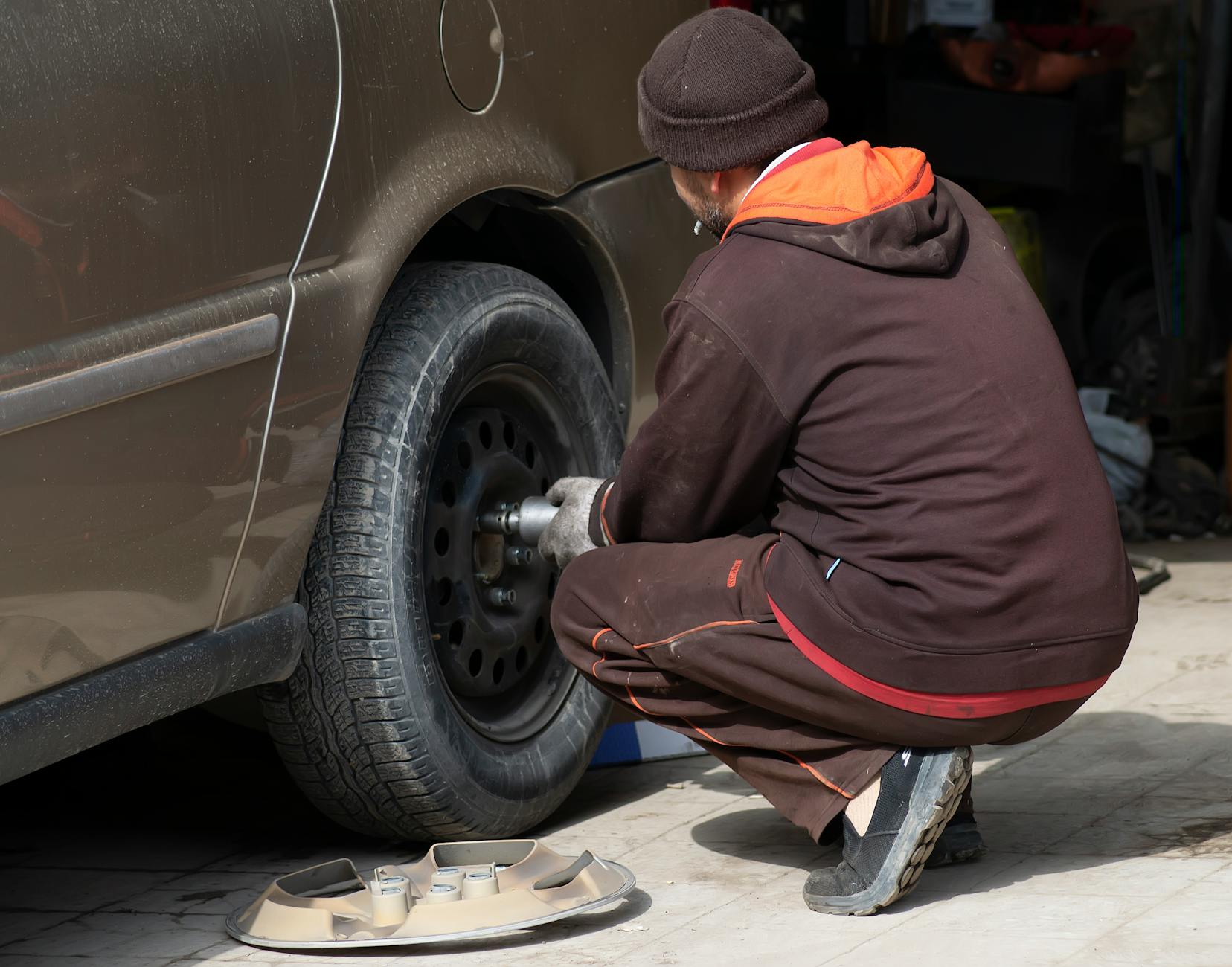 A mechanic working on a car tire, changing it in an auto repair shop.