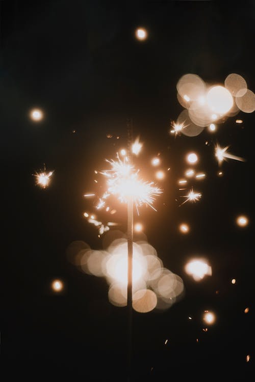 Close-up of a Sparkler and Blurry Sparks Flying against Dark Background 