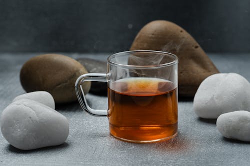 Close-up of a Cup of Hot Tea Standing between Rocks 
