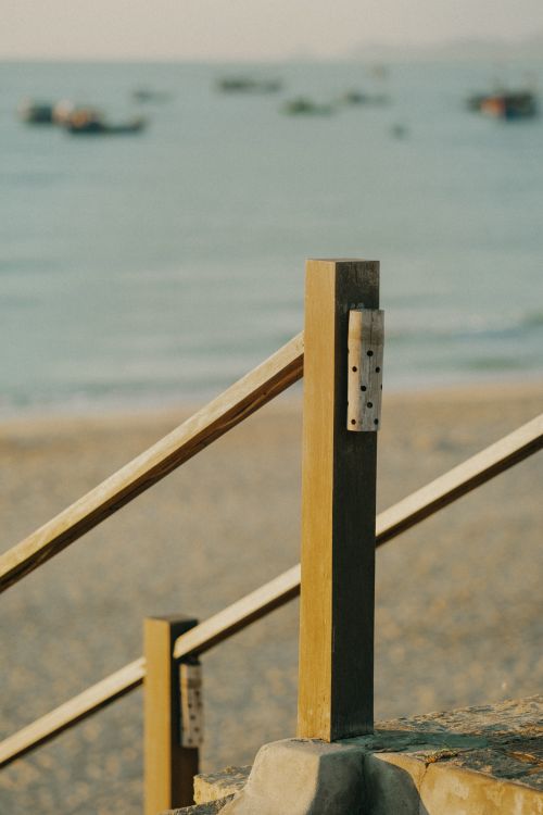 Free A soft focus image of a beach with a wooden handrail leading towards the sea. Stock Photo