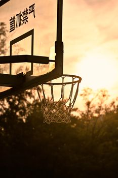 Silhouette of a basketball hoop at sunset, with a scenic backdrop. Perfect for sports themes.