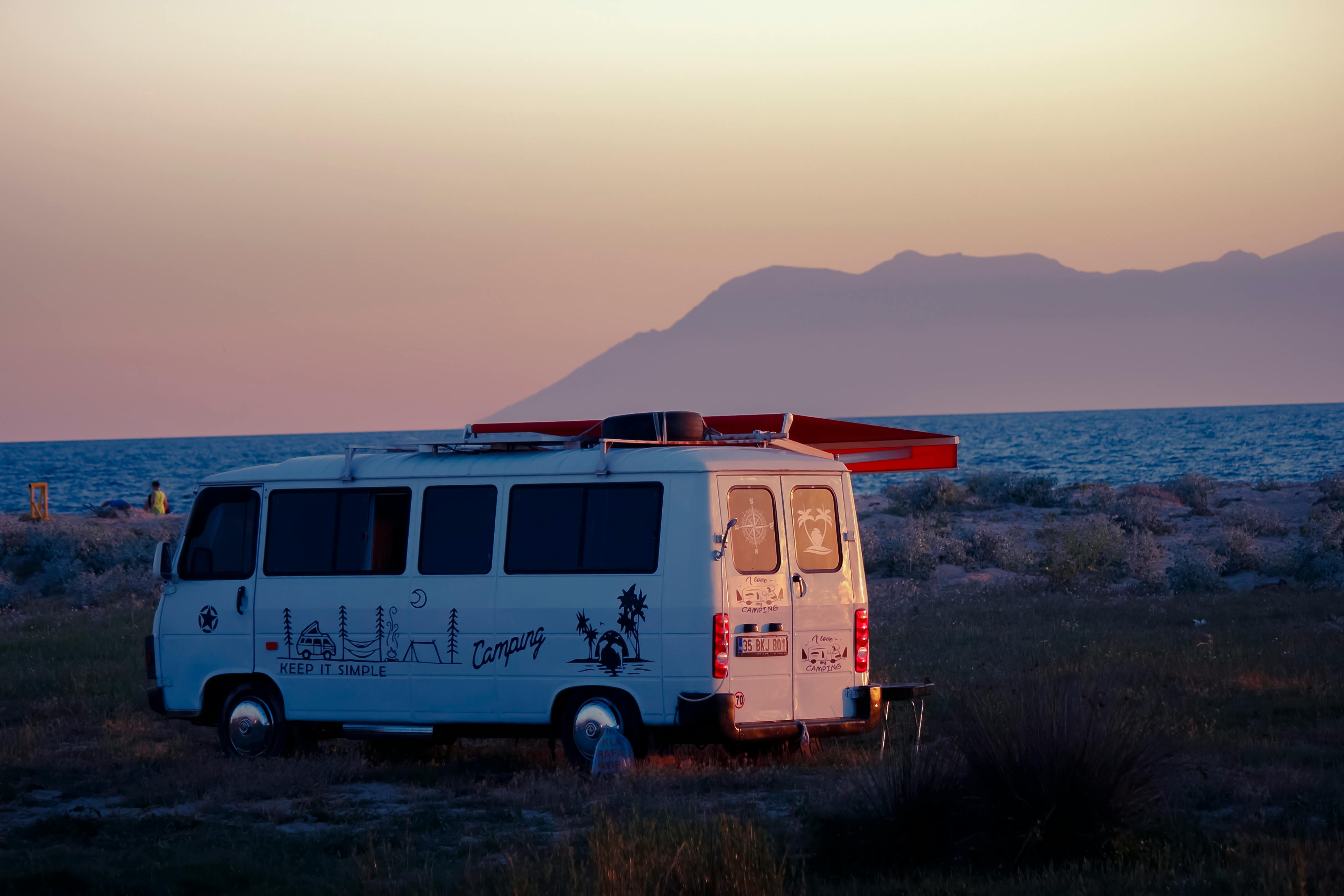 A serene scene with a camper van by the coast at sunset, perfect for travel and adventure themes.