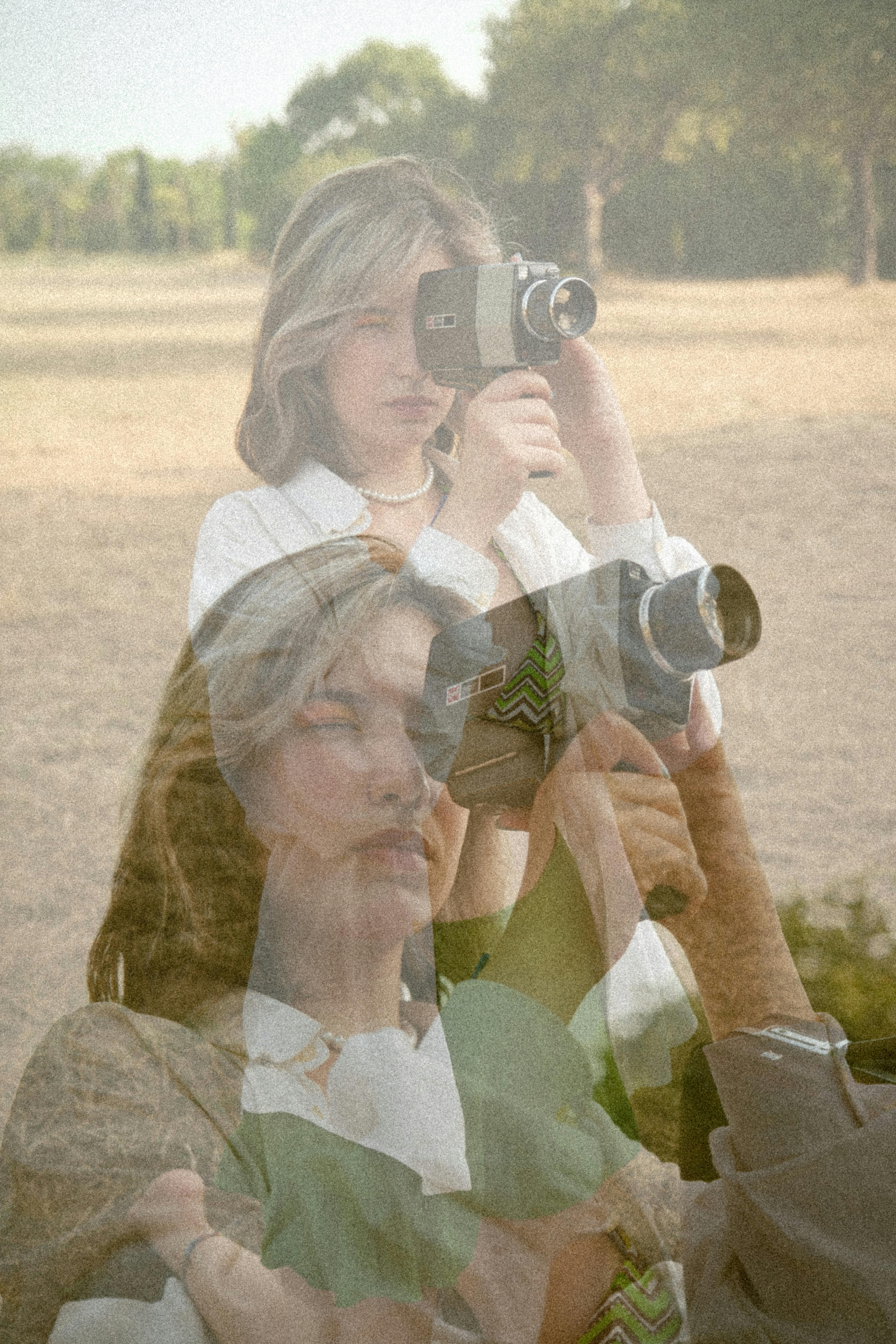 Artistic vintage double exposure of a woman with a camcorder in a rural landscape.