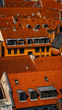 Aerial view of Copenhagen's urban rooftops with vibrant red tiles and classic architecture.