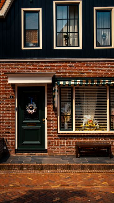A traditional Dutch brick house facade with festive decorations and large windows in Volendam, Netherlands.