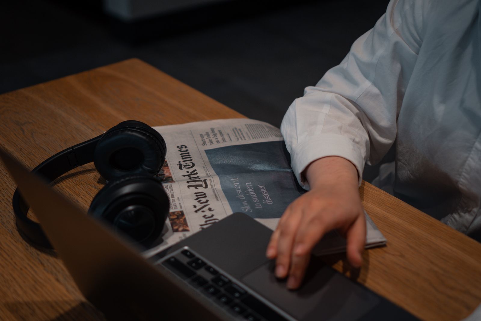 Bureau d'investisseur particulier avec ordinateur portable affichant un site d'actualité financière et journaux papier