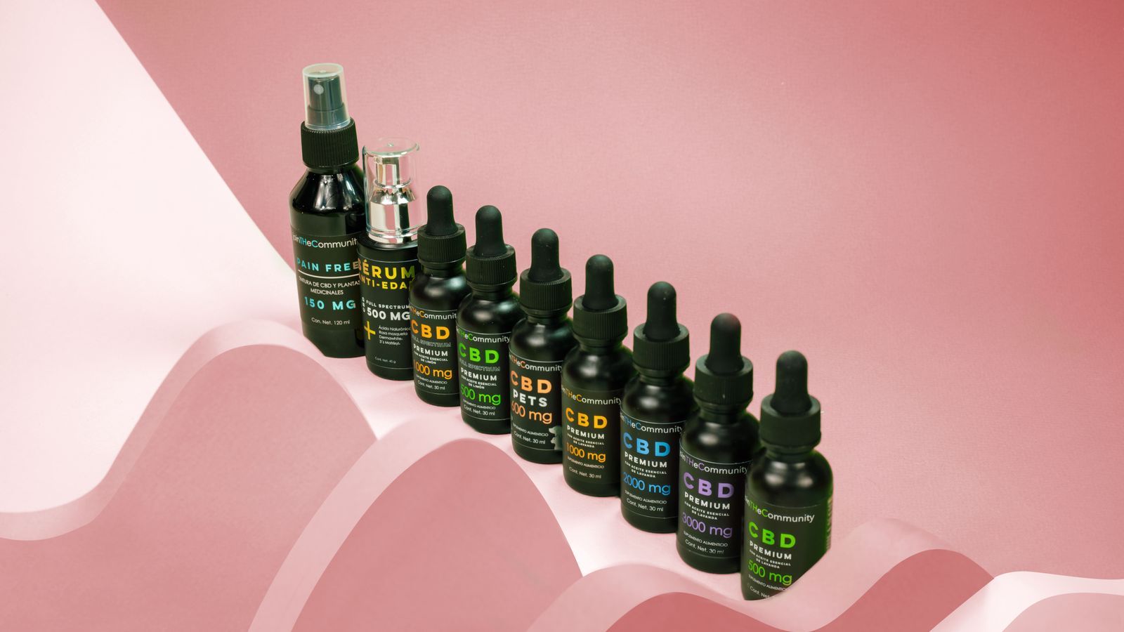 A row of CBD oil bottles displayed on a pink abstract background.