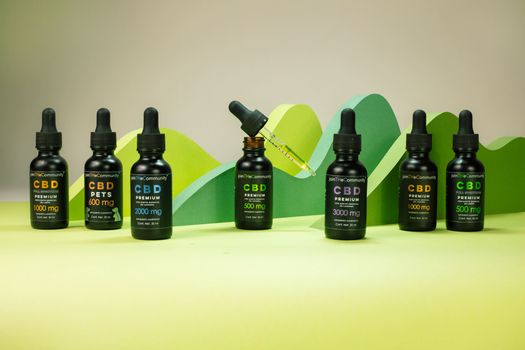 Array of CBD oil bottles with varied dosages on a green backdrop, ideal for wellness themes.