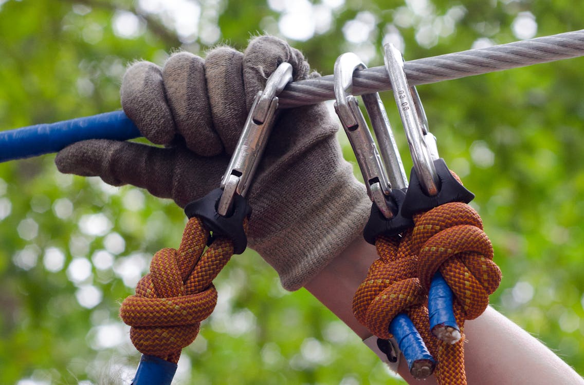 Person in Gray and Beige Gloves Holding on Gray Cable Wire