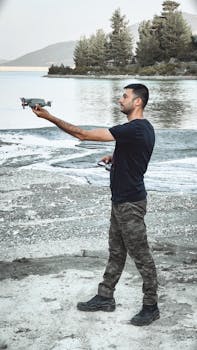 Man standing by the lake in Burdur, Türkiye, holding a drone in hand.