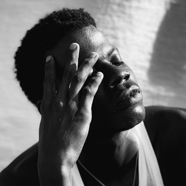 Dramatic black and white portrait of a man in deep thought, hand on forehead.