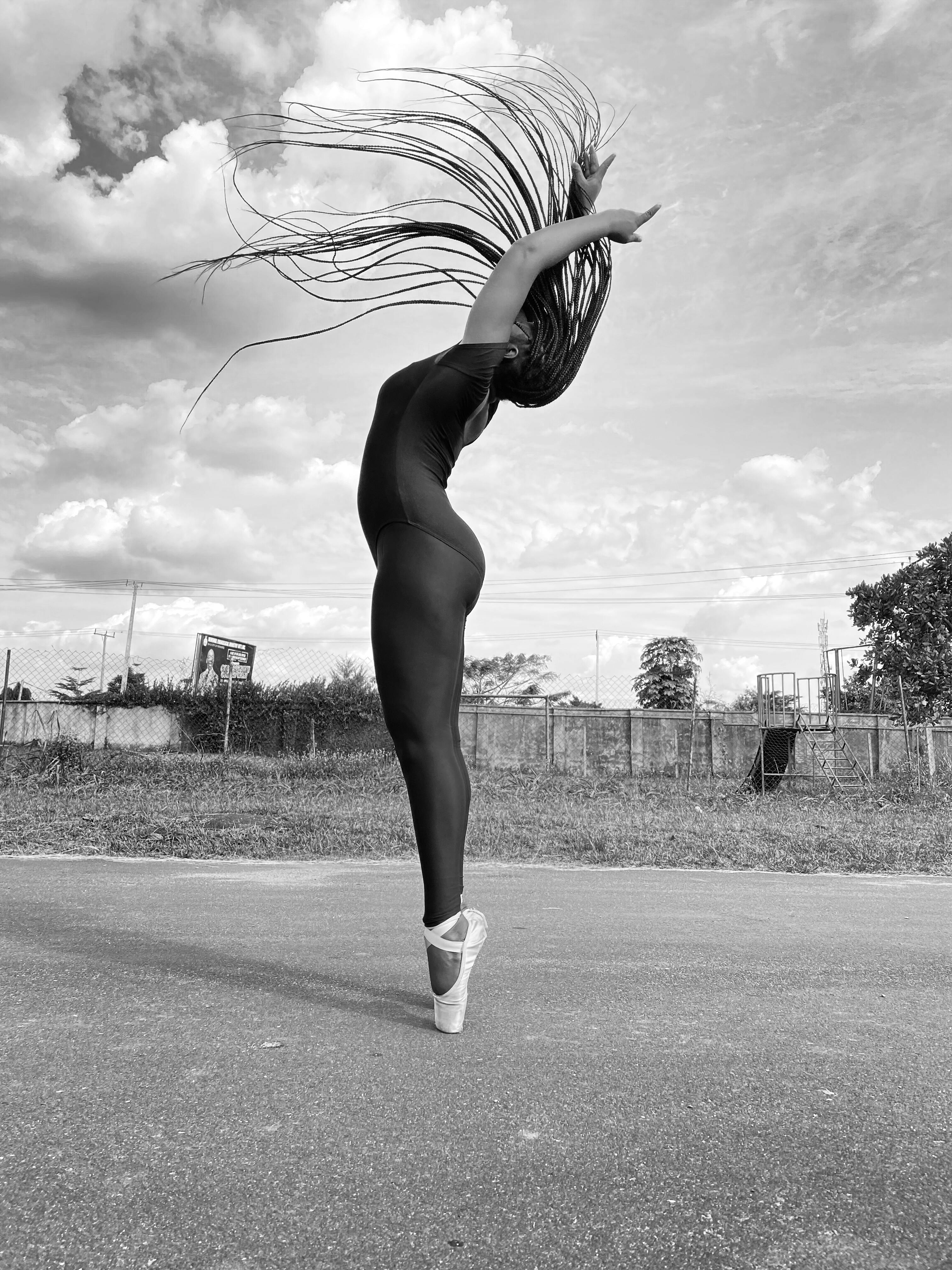 A dynamic black and white shot of a ballerina practicing outdoors, capturing her graceful movement.