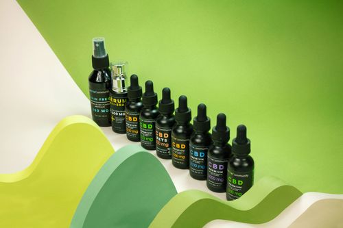 Free Creative layout of CBD oil bottles with vibrant green backdrop in studio setting. Stock Photo