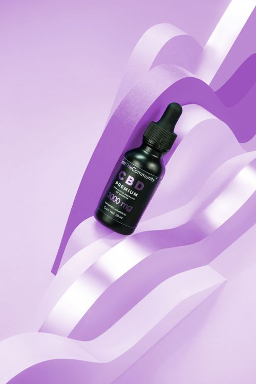 Free Black CBD serum bottle on dynamic purple paper background, capturing attention with elegance. Stock Photo