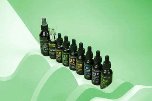 Free A collection of CBD oil and serum bottles arranged on a bright green background for skincare promotions. Stock Photo