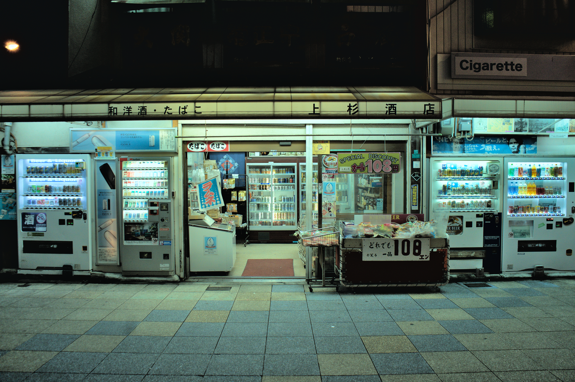 A view of a Japanese convenience store at night in Osaka with vending machines.