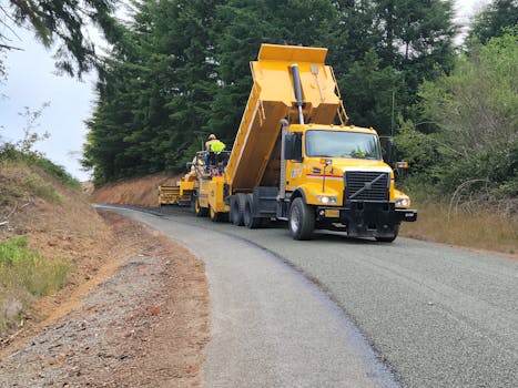 A yellow dump truck paving a forest road in Langlois, Oregon, USA.