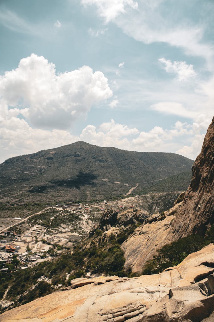 A Person Standing On Top Of A Rock Looking At The Valley Below