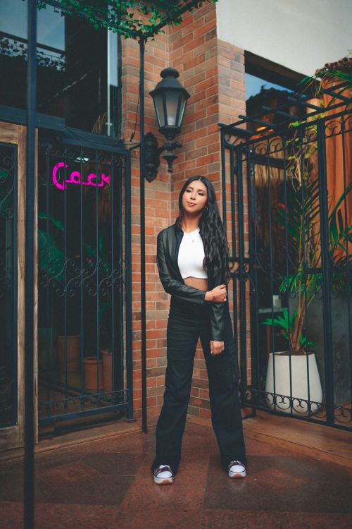 Free Stylish young woman posing in urban setting with leather jacket and long hair. Stock Photo
