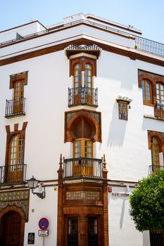 Charming white facade with ornate windows in Seville's residential district.