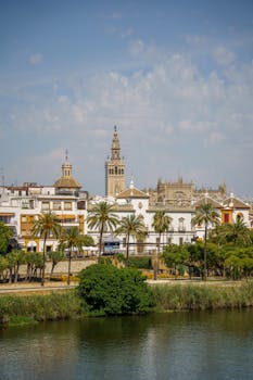 Idyllic view of Seville's historic buildings and river under a clear sky.
