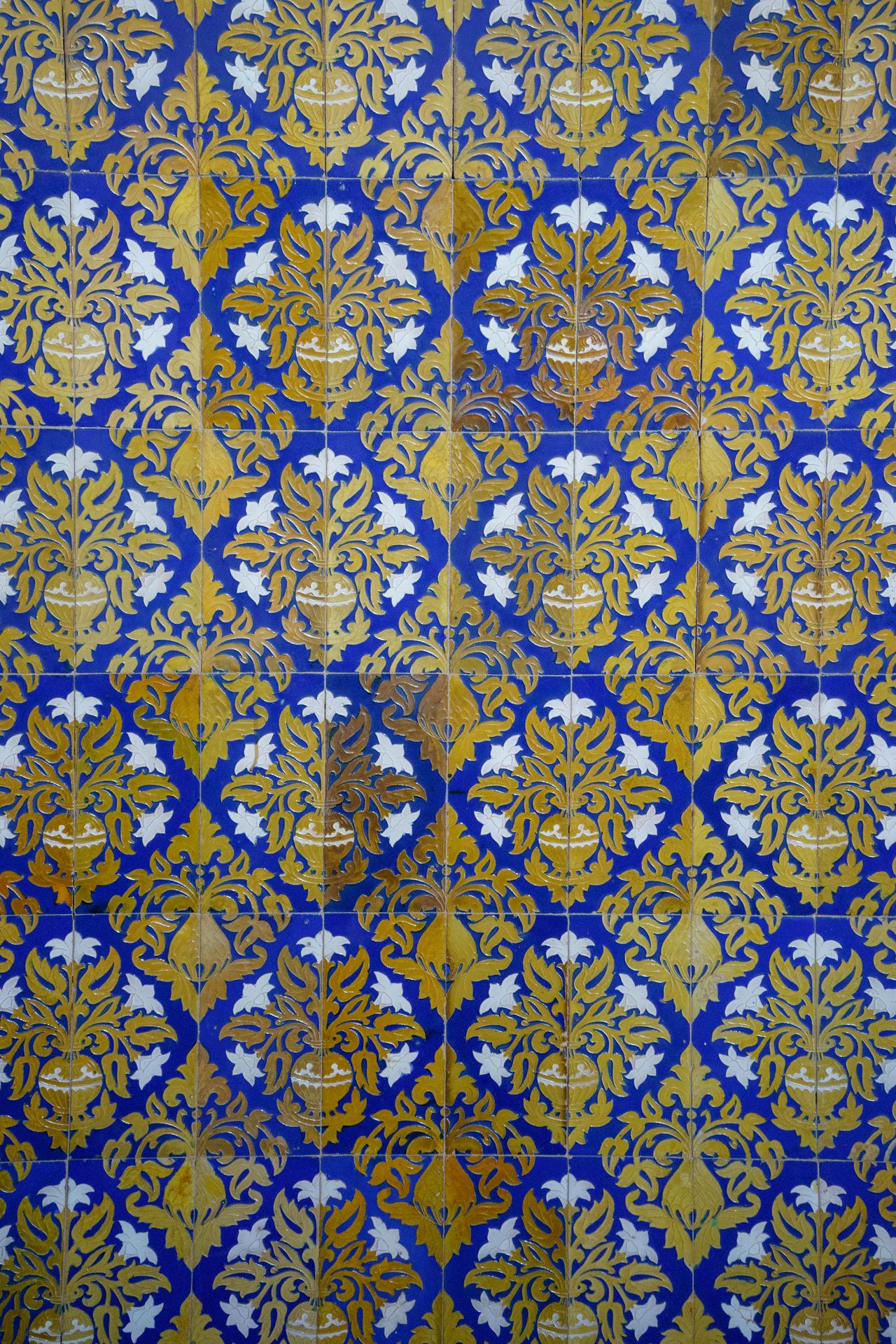Blue and yellow ornate floral tiles create a stunning decorative wall pattern in Seville, Spain.