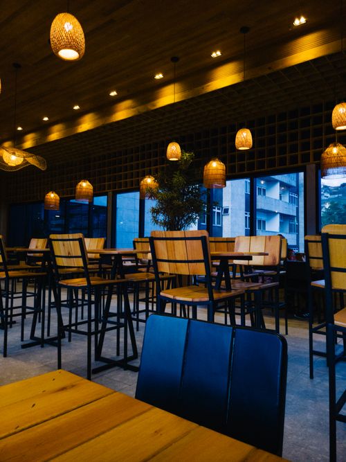 Free Warm and inviting cafe interior featuring high chairs, wooden tables, and stylish lamps. Stock Photo