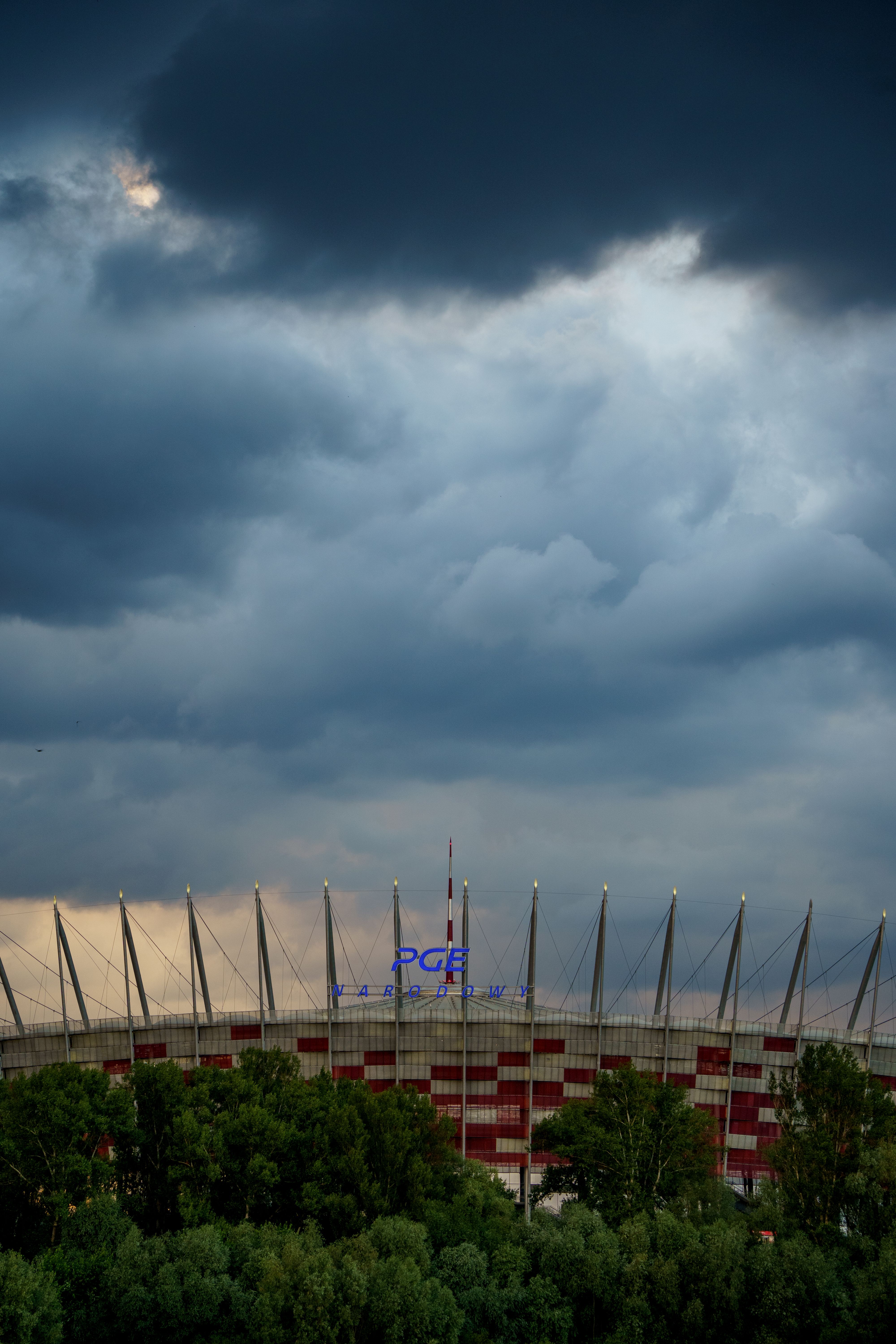 PGE Narodowy Stadium under stormy skies in Warsaw, Poland, showcasing a dramatic and moody atmosphere.