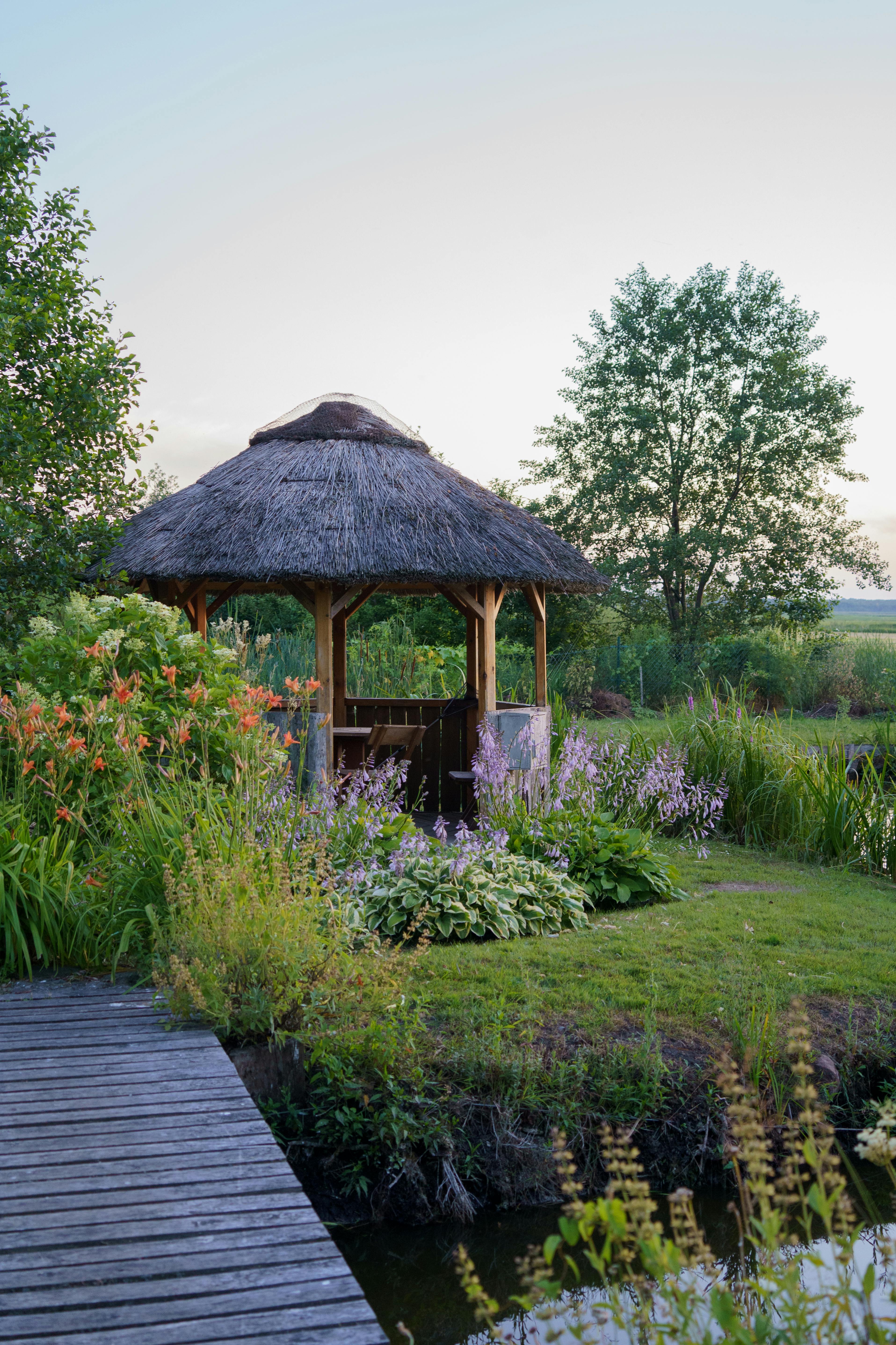 Rustic gazebo surrounded by a serene flower garden in Dolistowo Nowe, Poland.