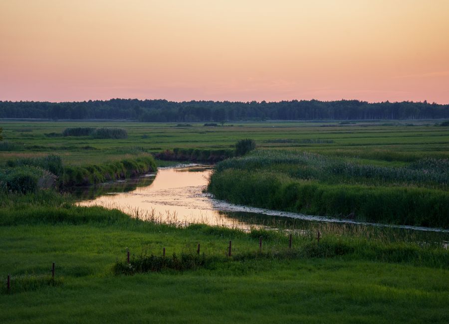 A tranquil rural river landscape at dusk in Dolistowo Nowe, Podlaskie Voivodeship, Poland.
