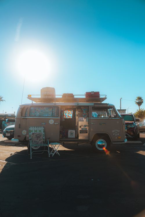 Free Vintage camper van in a sunny parking lot with travel gear aboard. Stock Photo