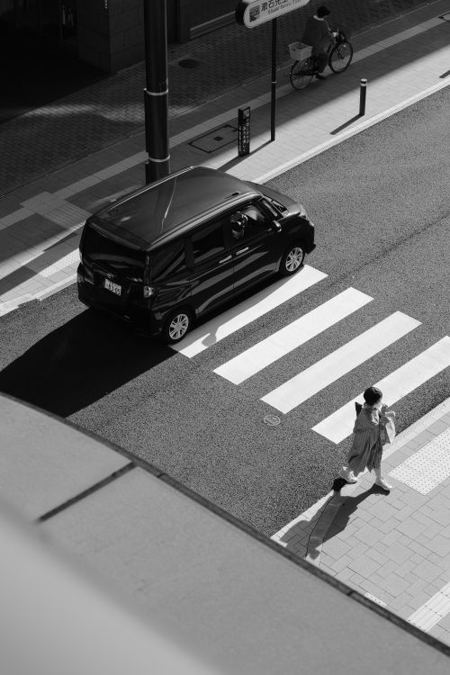 Free A woman crosses the street in a black and white urban setting, high angle view. Stock Photo
