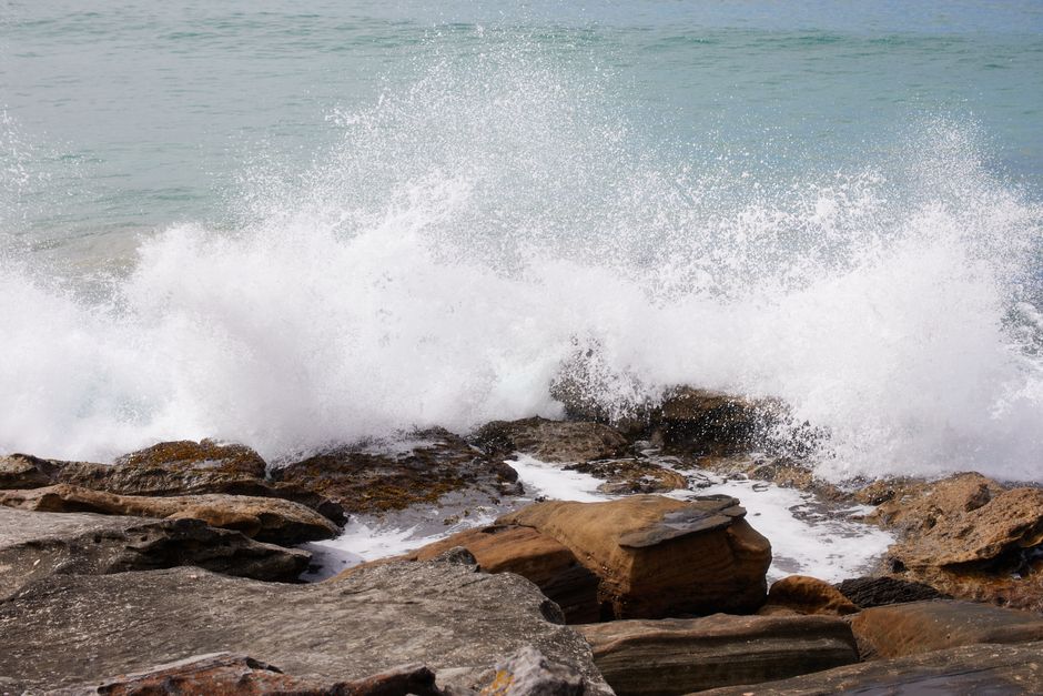 Powerful ocean waves crashing onto a rugged rocky coastline, showcasing the beauty and force of nature.