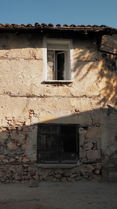 Free Rustic stone cottage exterior with open window under a sunny blue sky. Stock Photo