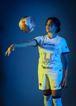 A female soccer player in uniform poised with a soccer ball, showcasing athletic prowess.