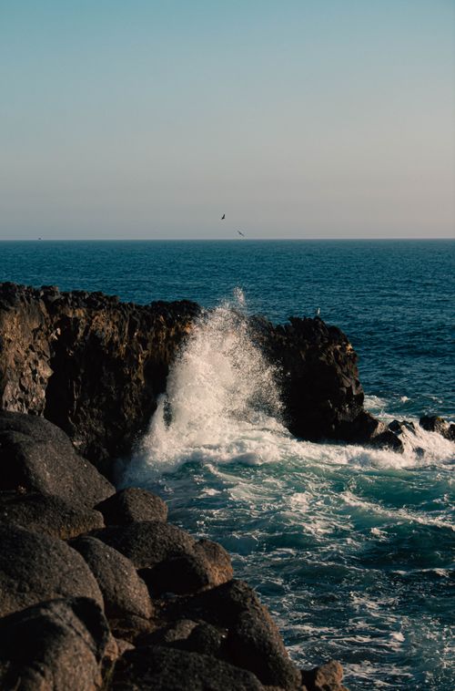 Free Majestic view of waves crashing against rugged cliffs along the Rosarito coastline at sunset. Stock Photo