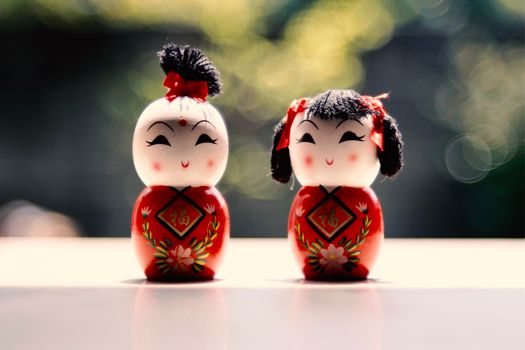 Close-up of hand-painted wooden Chinese dolls with floral patterns, beautifully lit by sunlight.