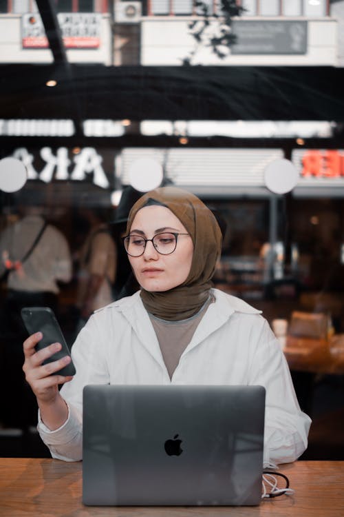 Woman Using a Laptop and a Smart Phone in a Restaurant 