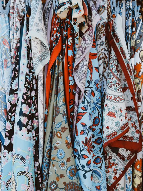 Free A vibrant display of various patterned shawls hanging vertically, featuring intricate designs and rich colors. Stock Photo