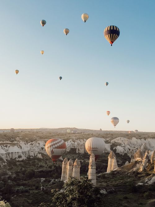 Free Scenic view of hot air balloons floating above the rock formations in Cappadocia, Turkey. Stock Photo