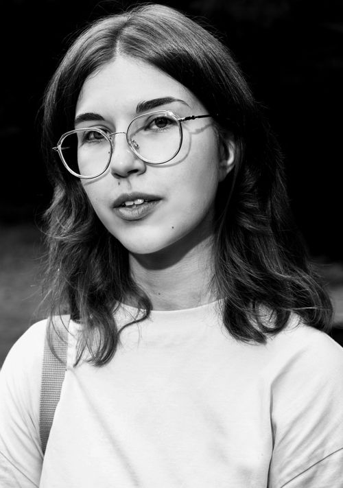 Free Elegant black and white photo of a young woman with glasses in a studio setting. Stock Photo