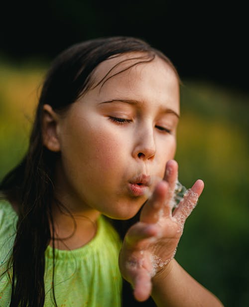 Girl Blowing Bubbles from Hand