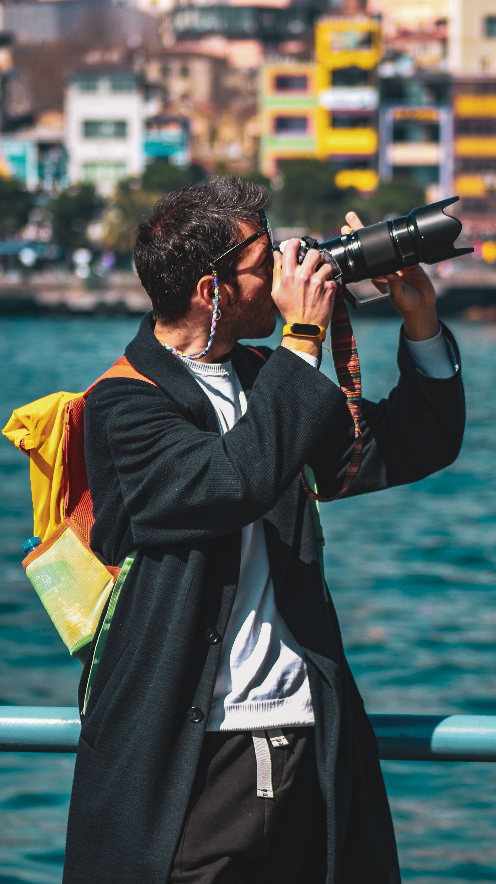 Man capturing scenic views with a DSLR camera at a vibrant waterfront location.