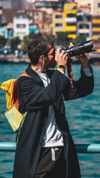 Man capturing scenic views with a DSLR camera at a vibrant waterfront location.